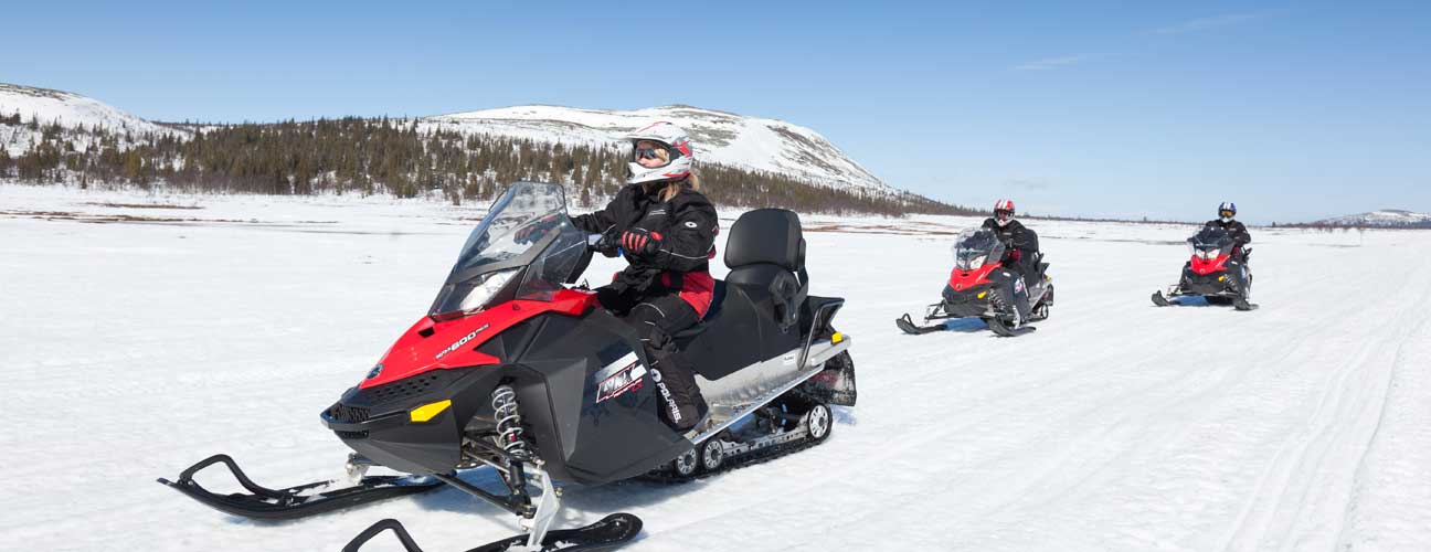 Tre skotrar som kör på fjället.