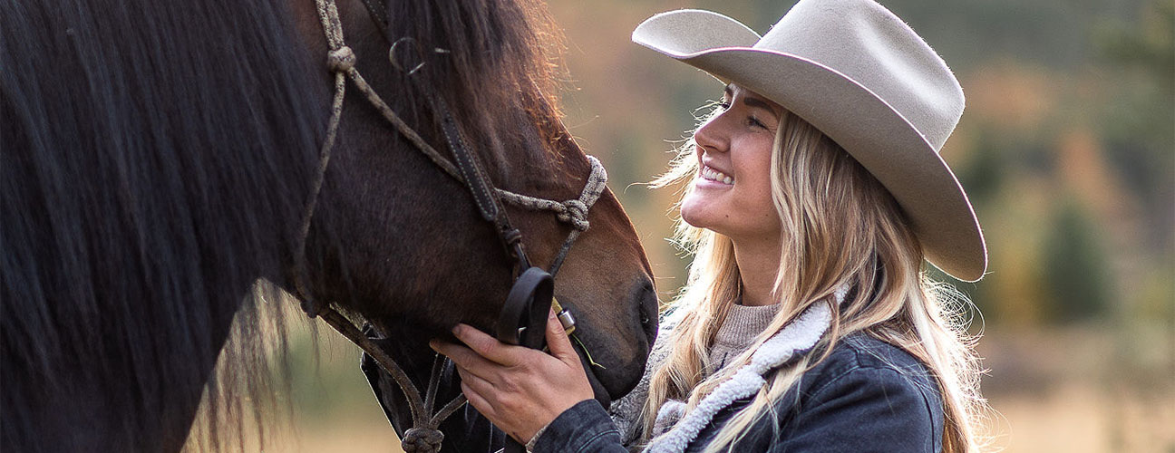Erica på Trumvallen Fjällridning klädd i hatt och ser på sin häst